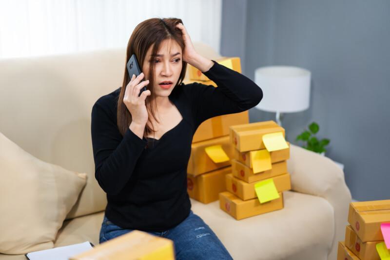 stressed woman entrepreneur talking problem smartphone selling product online home office