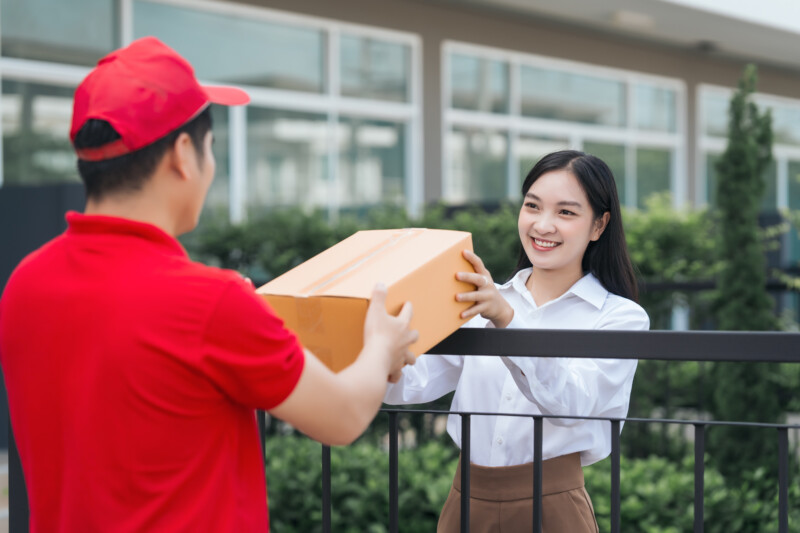 asian people received product box from male delivery service person modern ecommerce home deliveries convenient shopping experience trustworthy doorstep service captured moment